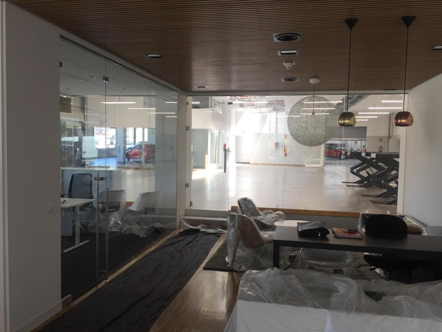 Interior de oficina moderno con paredes de vidrio, techo de madera y escritorios en primer plano.