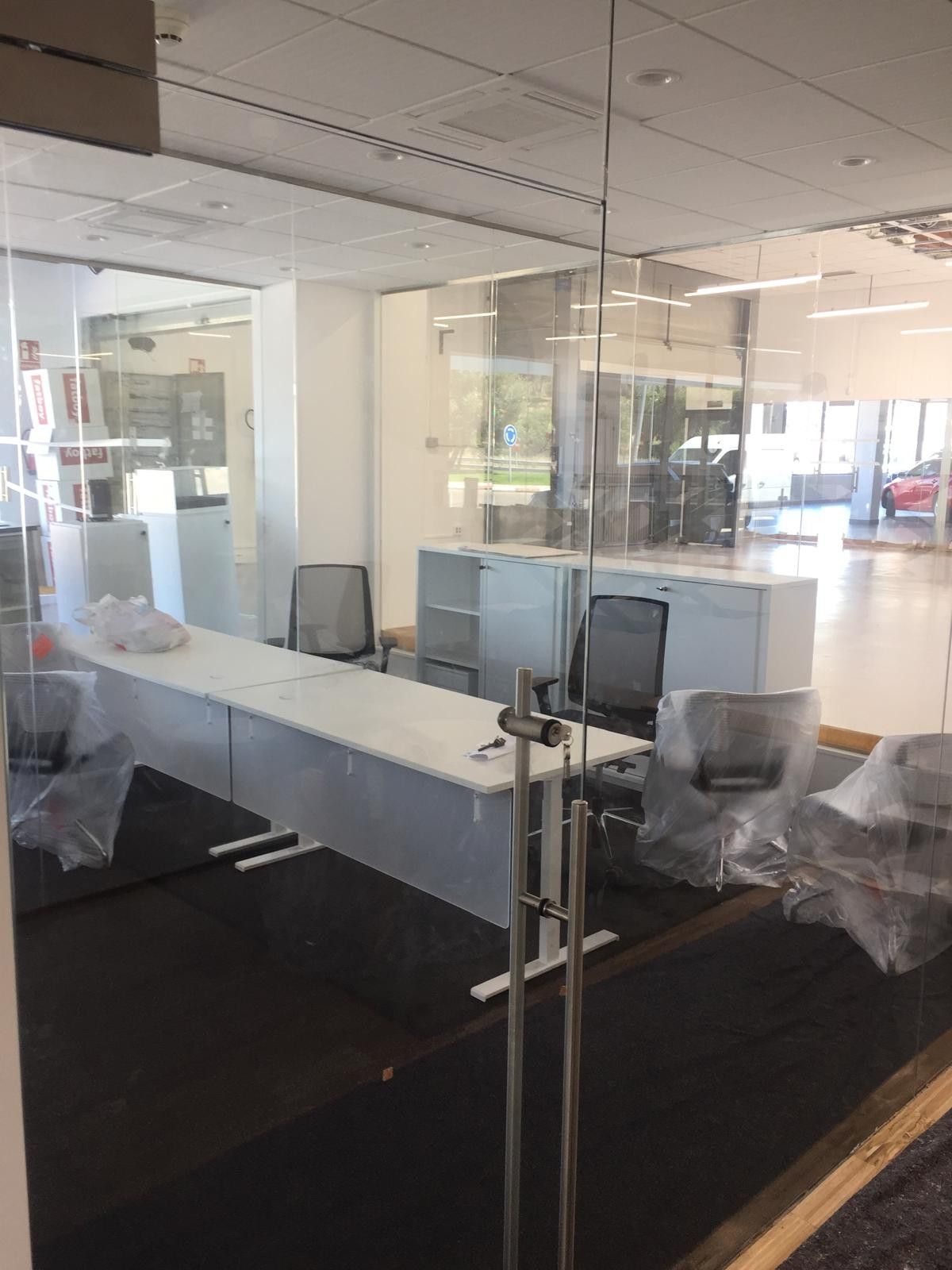 Sala de reuniones de cristal con mesa, sillas y vistas a la ciudad.