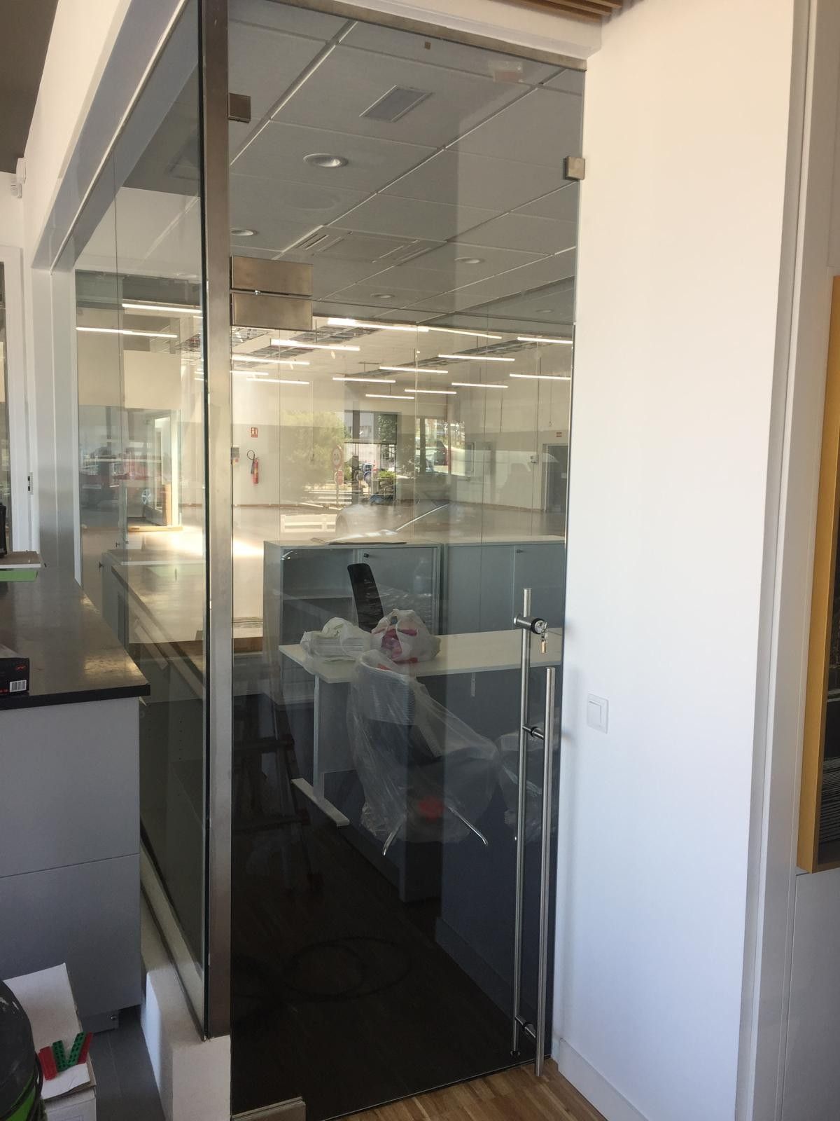 Sala de reuniones acristalada con una persona sentada en un escritorio en un pasillo luminoso.