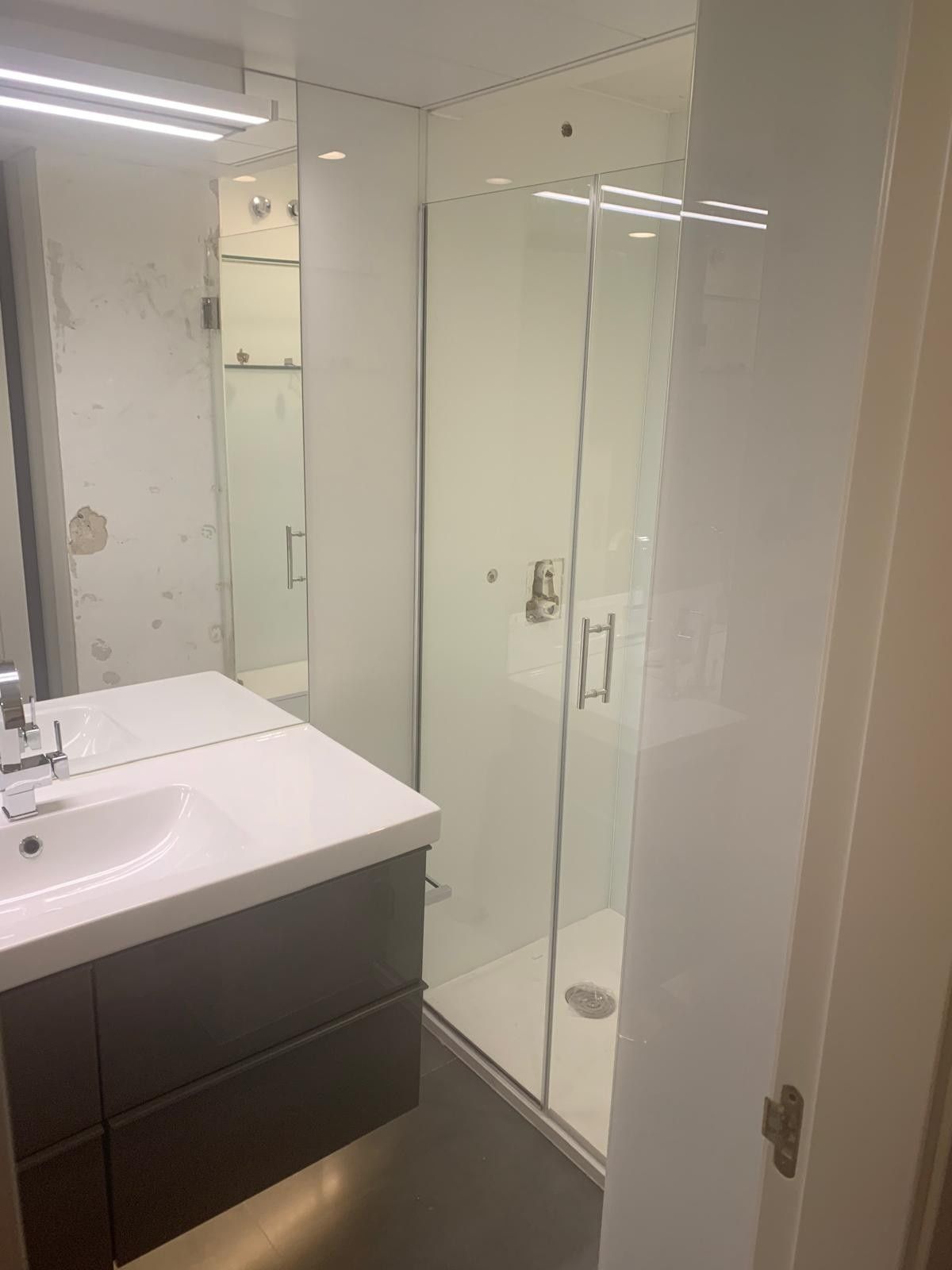 Baño moderno con lavabo y cabina de ducha de cristal.