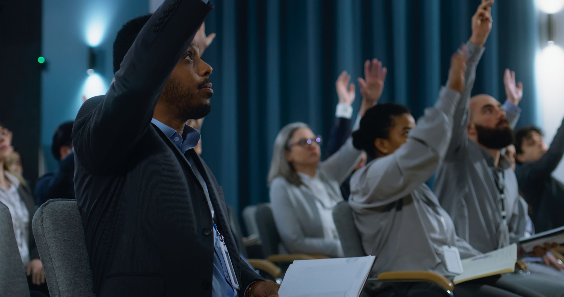 In einem Konferenzraum hebt eine Gruppe von Menschen ihre Hände.
