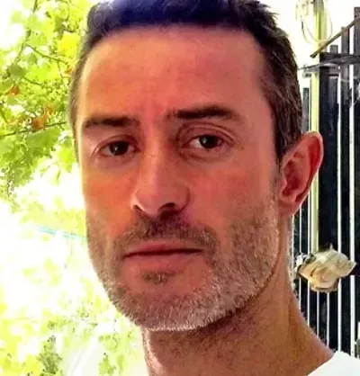 Retrato en primer plano de un hombre con cabello corto y oscuro y barba incipiente