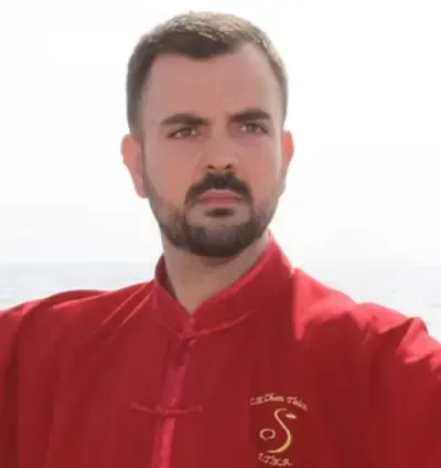 Hombre con camisa roja de pie al aire libre contra un cielo brillante