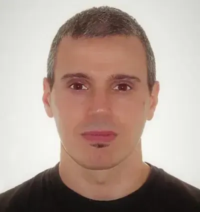 Retrato de estudio de un hombre con cabello corto y expresión neutra sobre un fondo blanco.