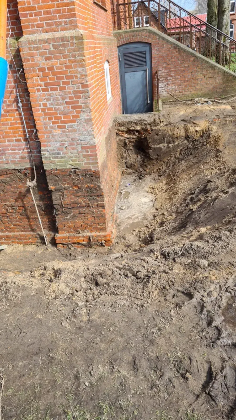 Backsteingebäude mit ausgehobener Fläche, Tür und Erde.