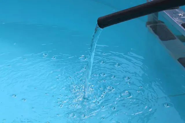 Una tubería está vertiendo agua en una piscina.