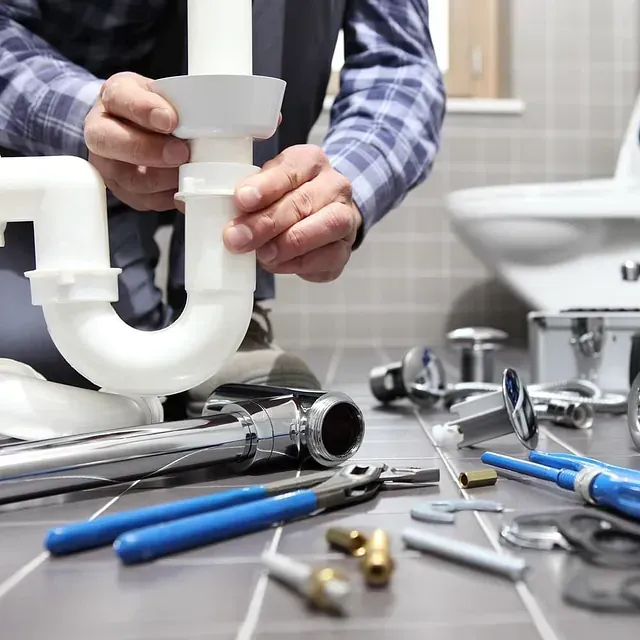 Un fontanero está trabajando en una tubería del fregadero de un baño.