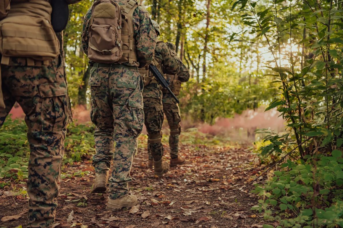Un grupo de soldados camina por un sendero en el bosque.