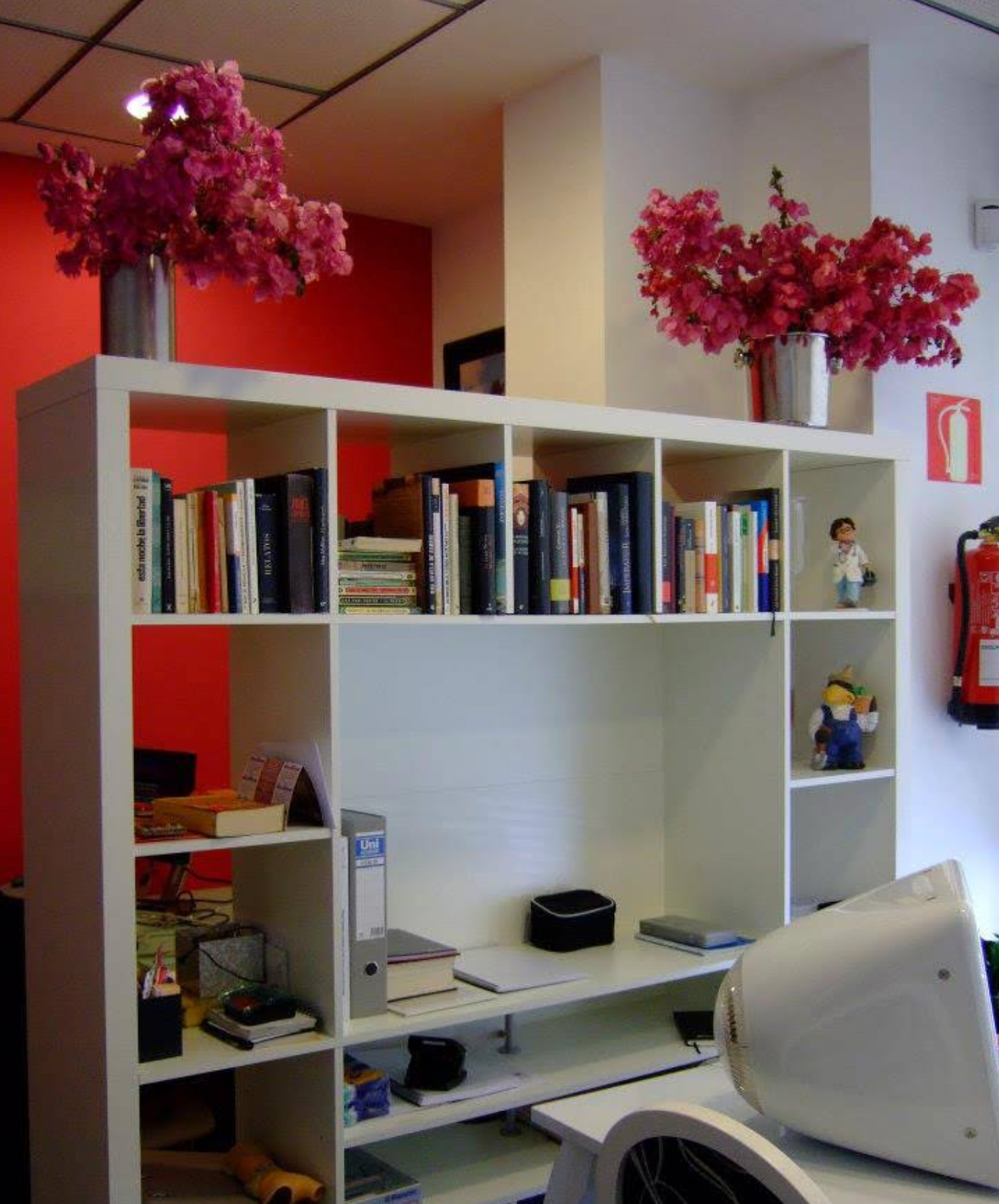 Un estante blanco con libros y flores.