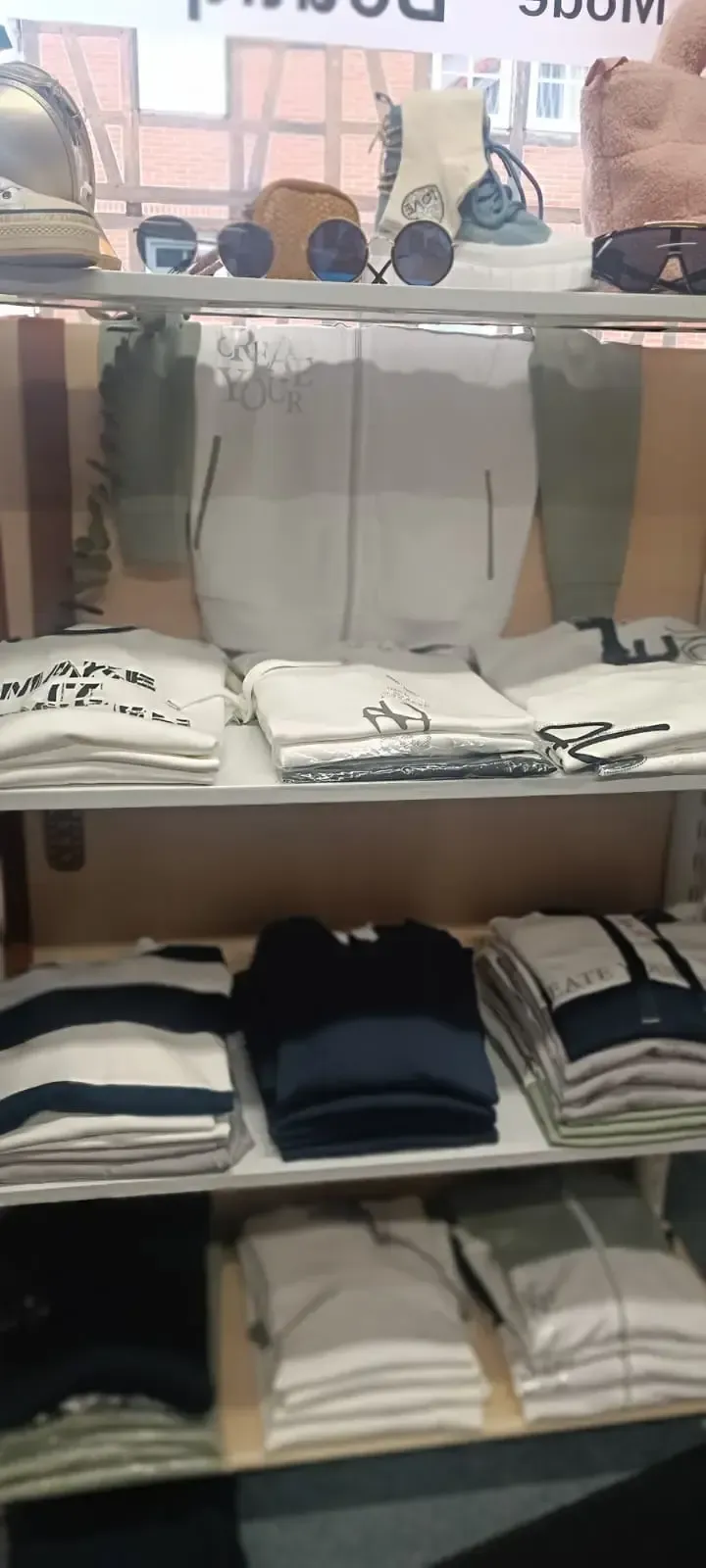 Regale voller ordentlich gefalteter Hemden in Weiß, Schwarz und Marineblau in einem Bekleidungsgeschäft