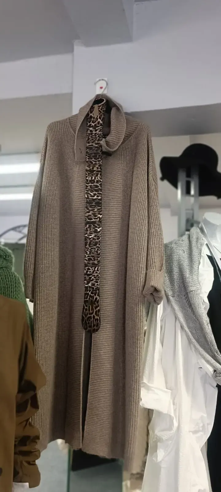 Brauner, langer Strickcardigan auf einem Kleiderbügel in einem Bekleidungsgeschäft
