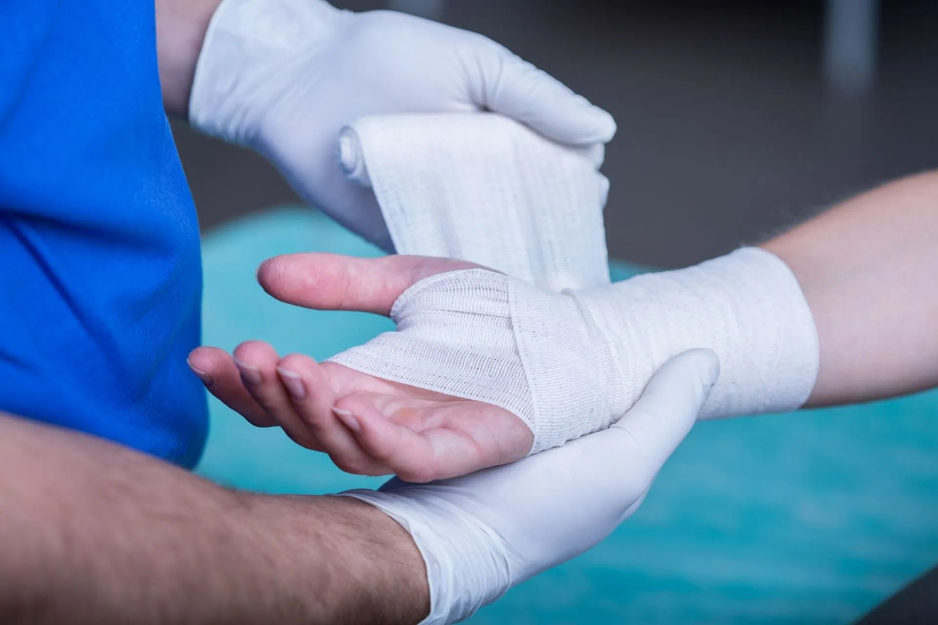 Des mains gantées enroulent un bandage autour d'un poignet blessé
