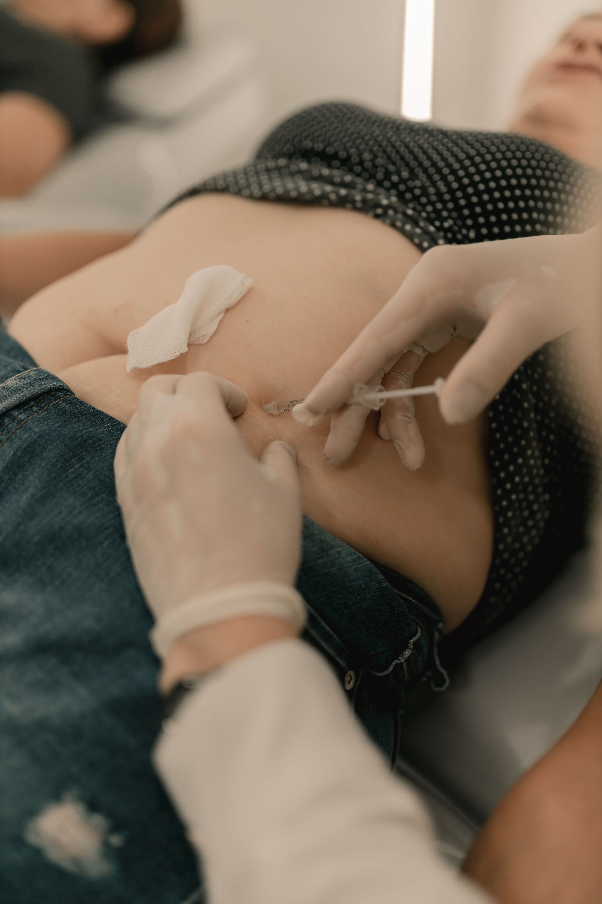 Lors d'une intervention médicale, des mains gantées insèrent une perfusion intraveineuse dans l'abdomen d'un patient.