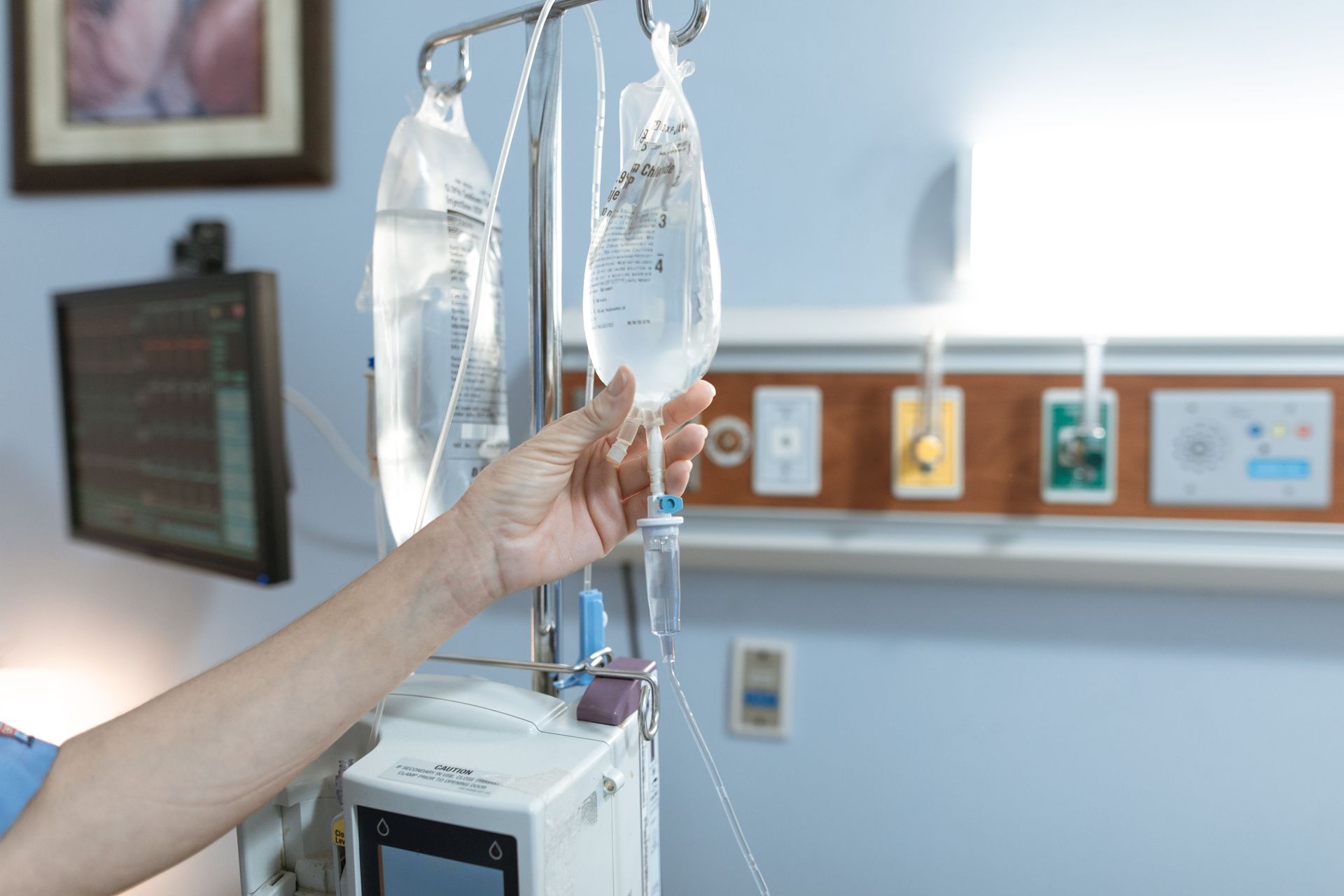 Ajustement manuel des poches de perfusion intraveineuse à côté d'un moniteur de lit d'hôpital