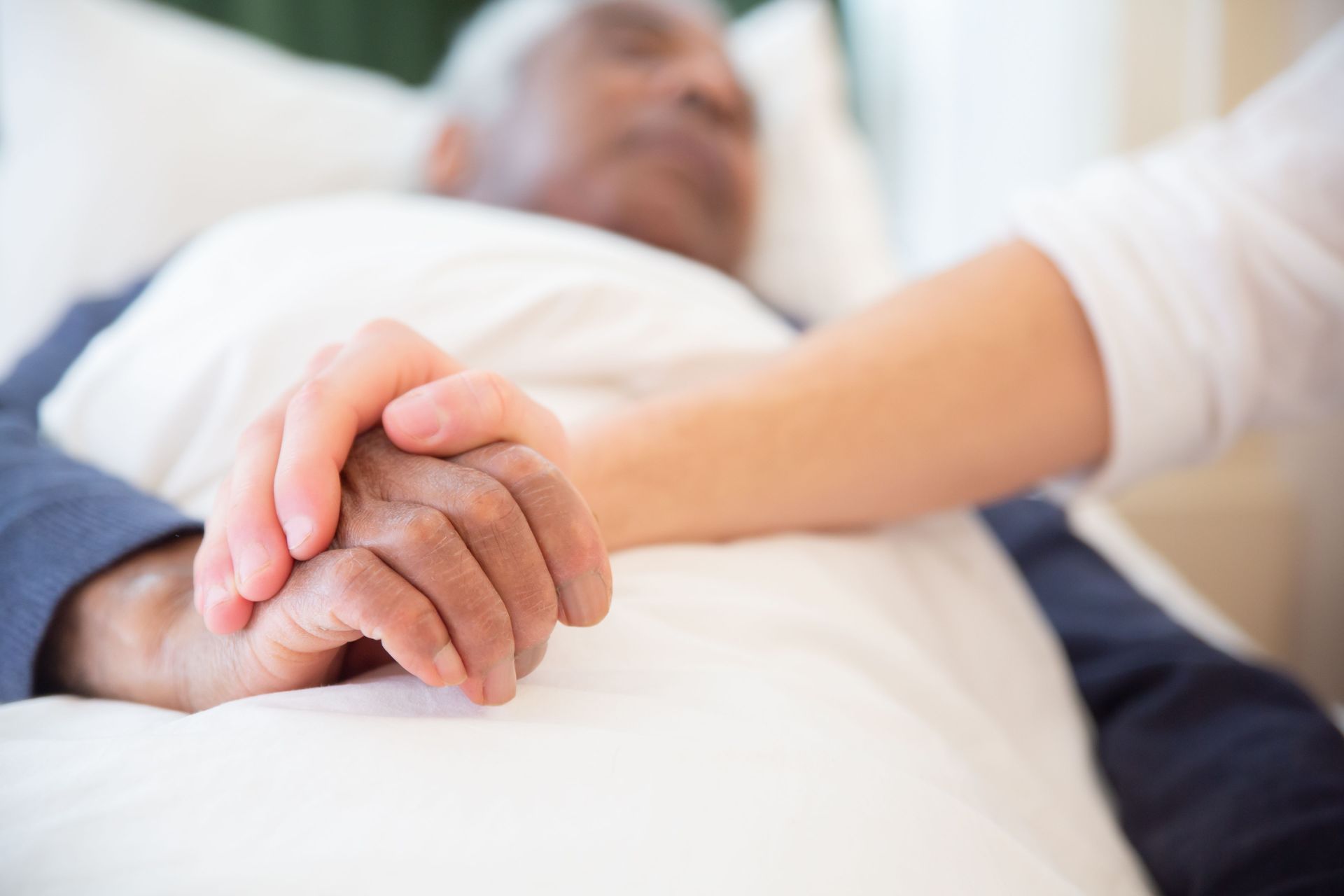 Main dans la main, une personne allongée et une autre personne, signe de réconfort et de soutien.