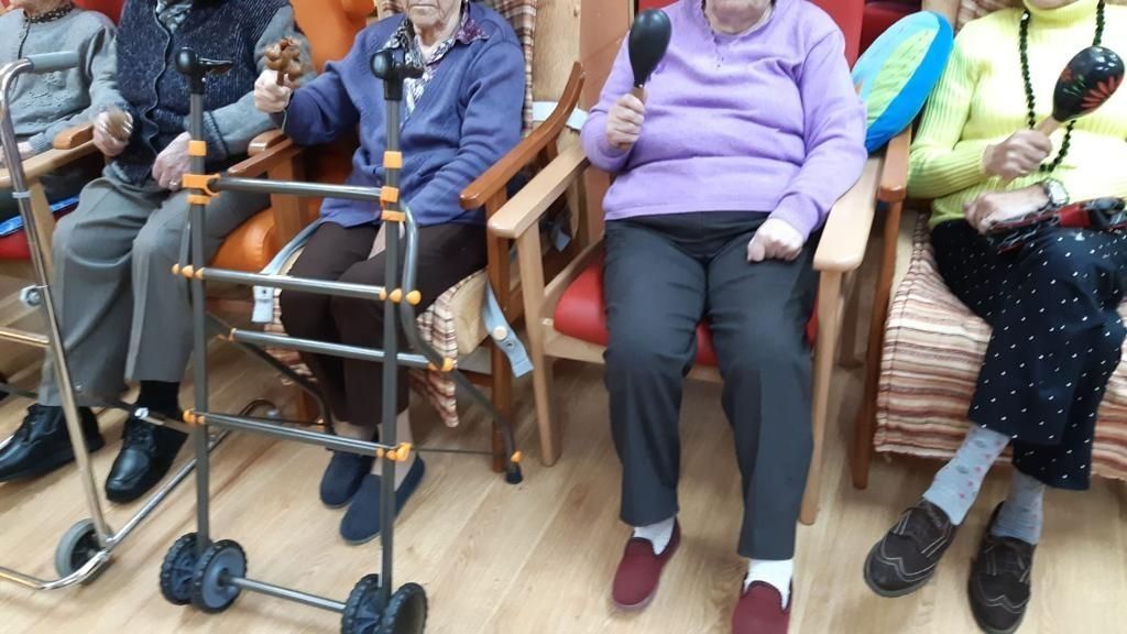 Un grupo de personas mayores sentadas en sillas con andadores.