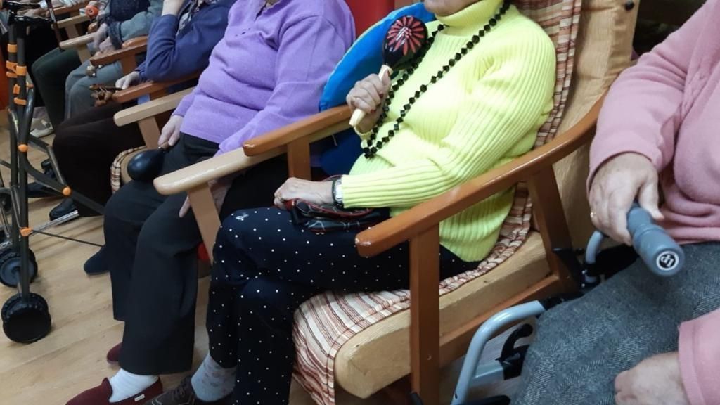 Un grupo de personas mayores están sentadas en sillas en una habitación.