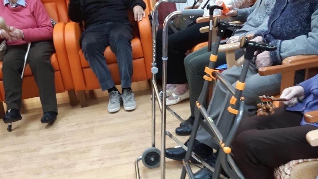 Un grupo de personas mayores sentadas en sillas con andadores.