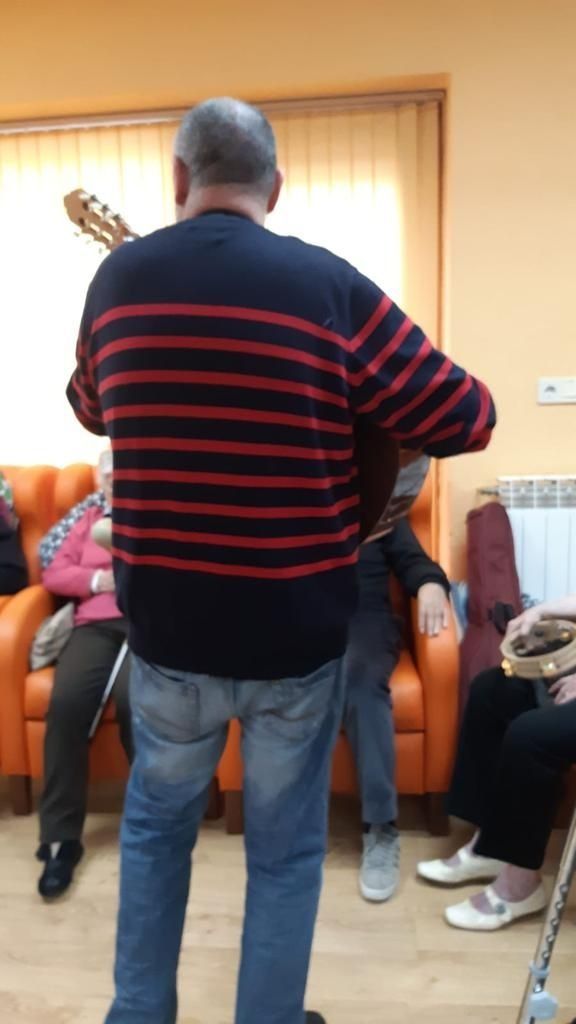 Un hombre tocando una guitarra delante de un grupo de personas.