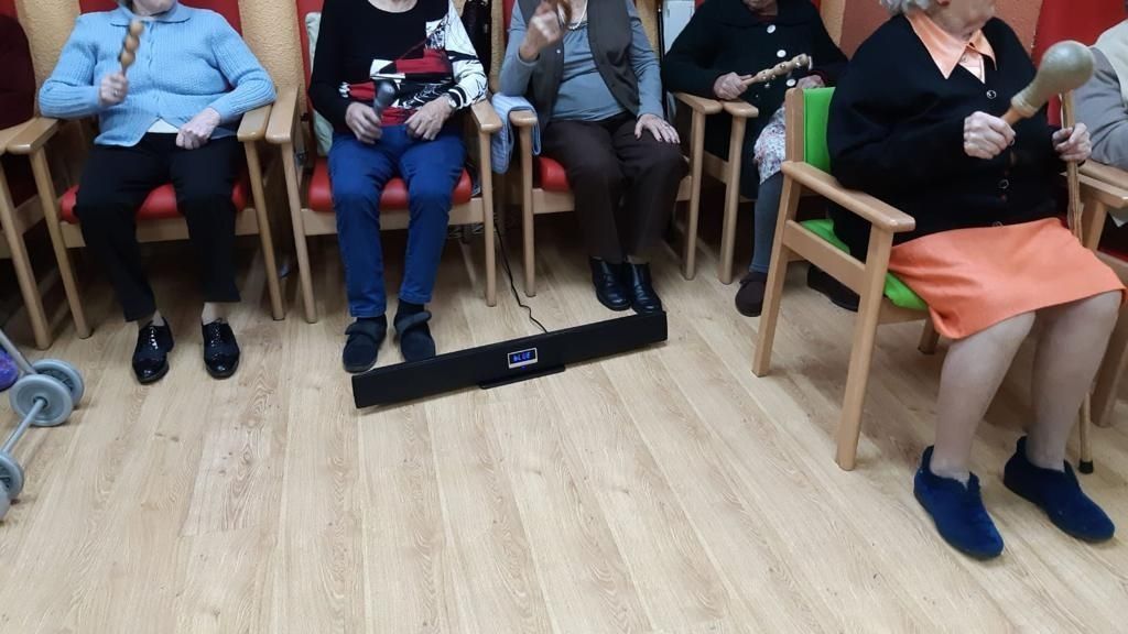 Un grupo de personas están sentadas en sillas tocando instrumentos musicales.