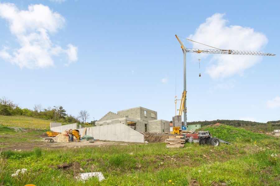 Chantier de construction avec une grue jaune à côté de bâtiments en béton inachevés sous un ciel bleu