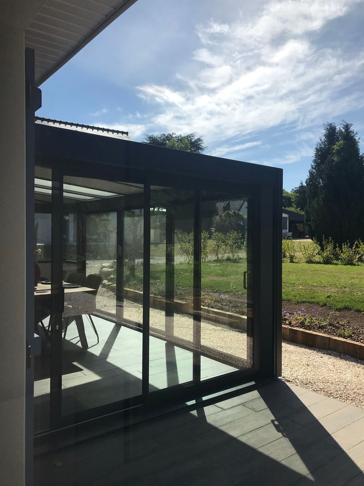 Véranda avec des murs en verre, cadre noir et portes coulissantes