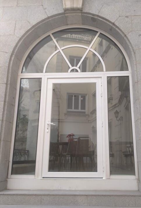 Una puerta blanca con una ventana de vidrio en el costado de un edificio.