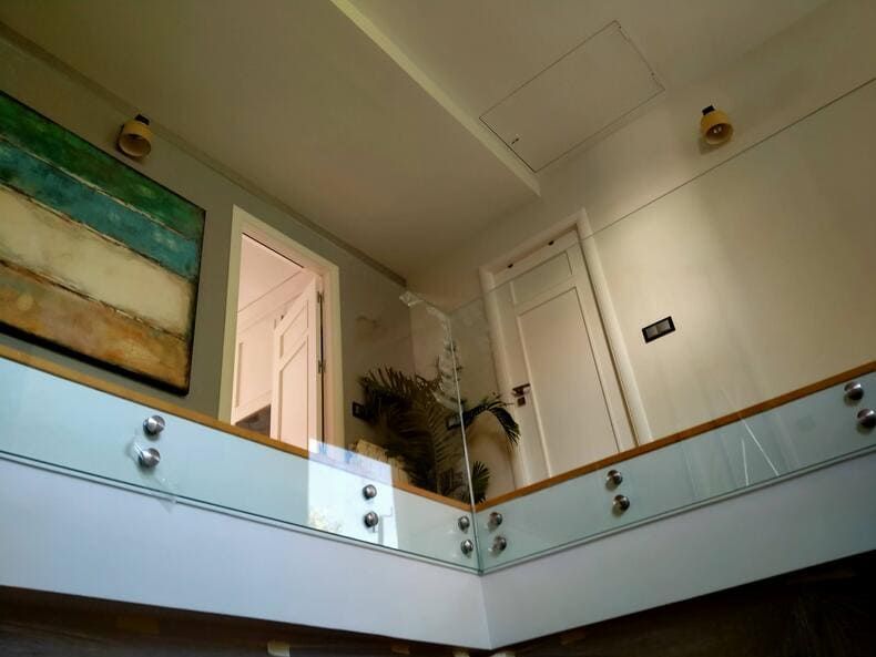 Una escalera con barandilla de cristal y un cuadro en la pared.