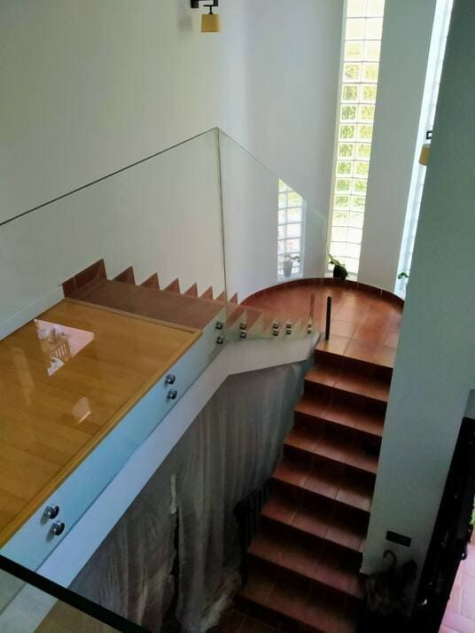 Una escalera con barandilla de cristal y escalones de madera.