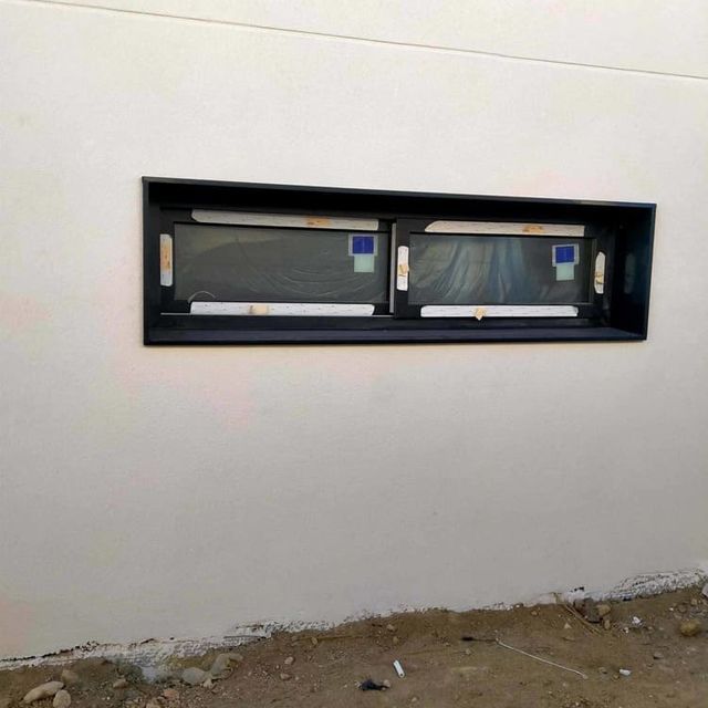 Una pared blanca con una ventana negra.