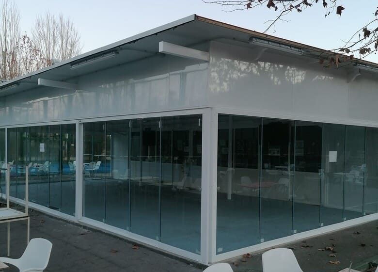 Un edificio blanco con muchas ventanas y sillas delante de él.