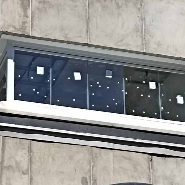 Un edificio con un balcón con mucho vidrio.