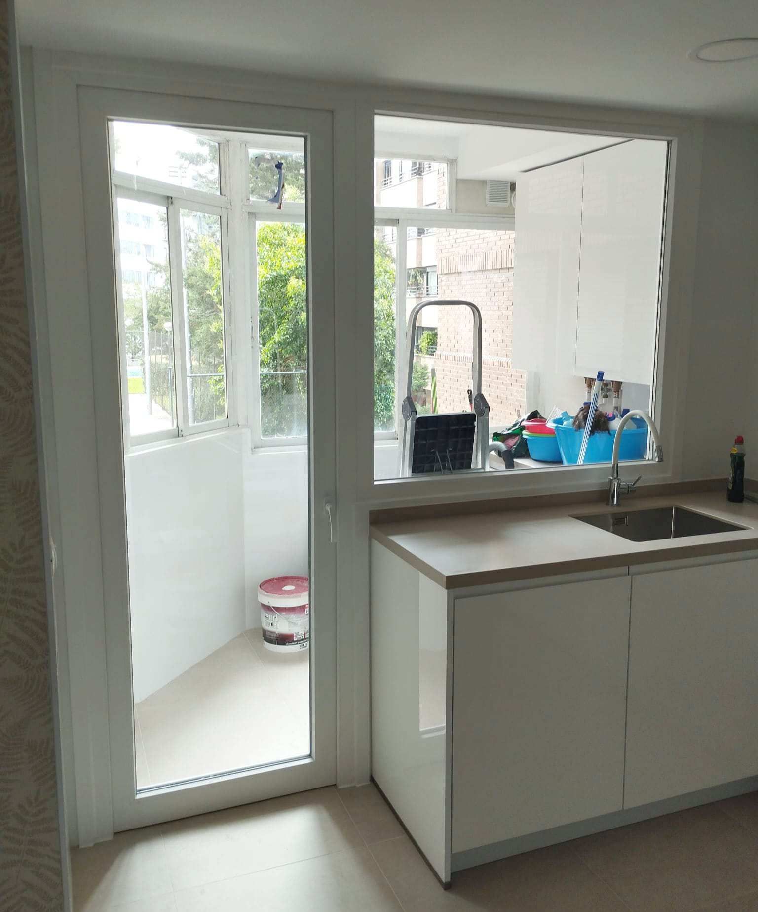 Una cocina con fregadero y una ventana que da a un balcón.
