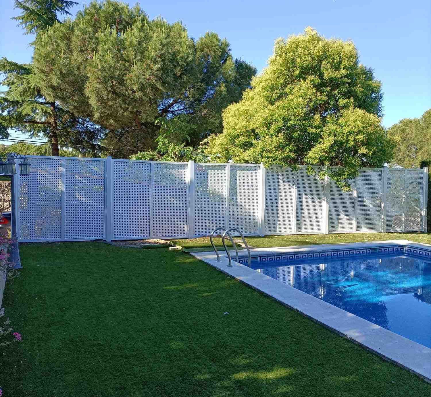 Una valla rodea una piscina en un patio trasero.