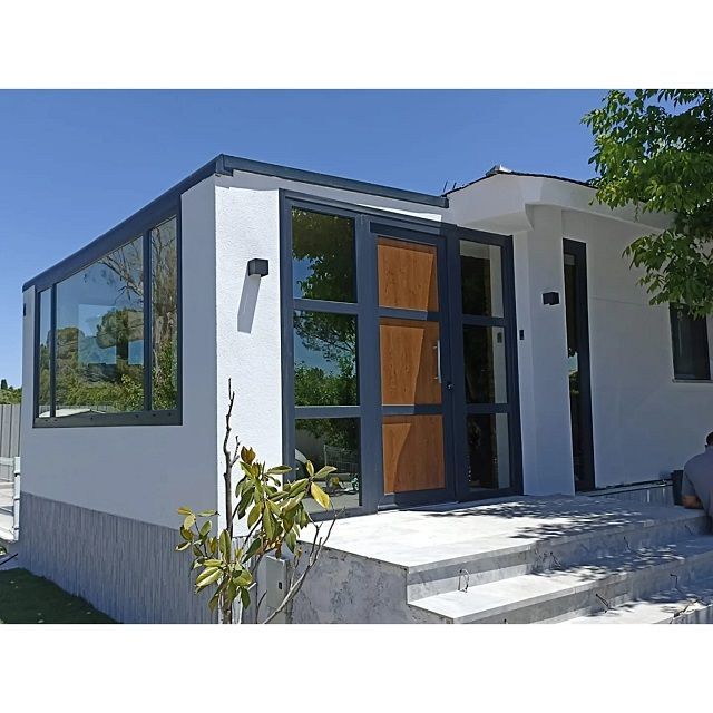 Una casa blanca con una puerta de madera y muchas ventanas.