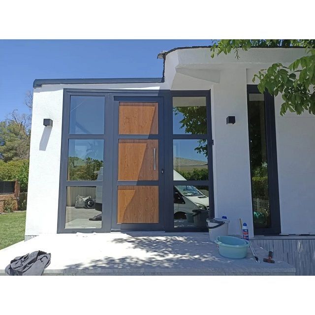 Una casa blanca con una puerta de madera y puertas corredizas de vidrio.