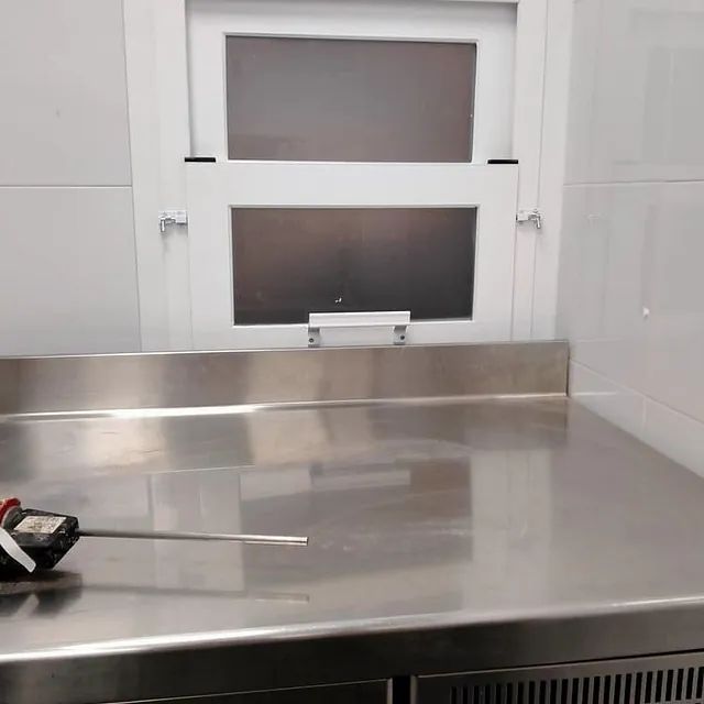 Un termómetro está colocado encima de un mostrador de acero inoxidable en una cocina.