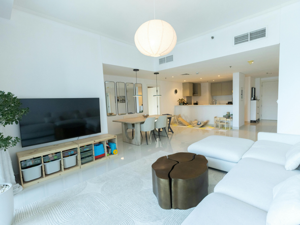 Spacieux salon blanc avec télévision, canapé, coin repas et cuisine ouverte.