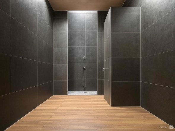 Salle de douche carrelée foncée avec parquet, plafonnier et deux cabines de douche.