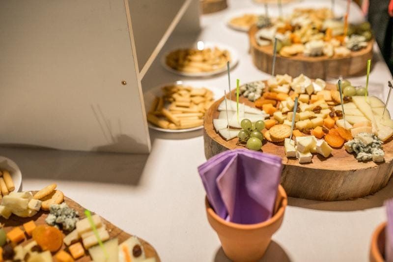 Bandejas de quesos y galletas dispuestas en círculos de madera, mesa preparada con bocadillos.