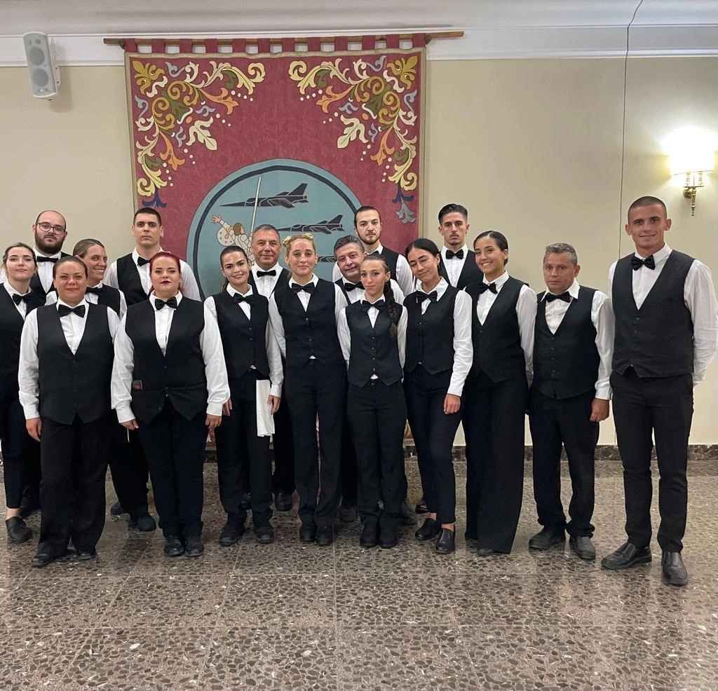 Grupo de servidores uniformados posando en el interior frente a un tapiz.