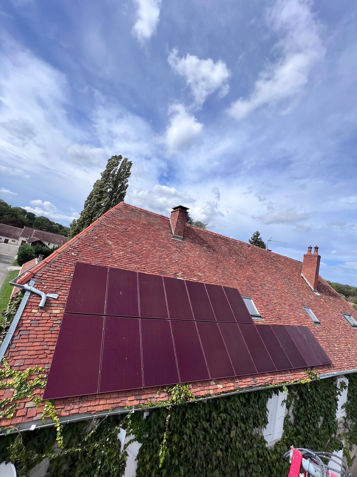 Pose de panneaux photovoltaïques rouges sur une toiture en tuile 