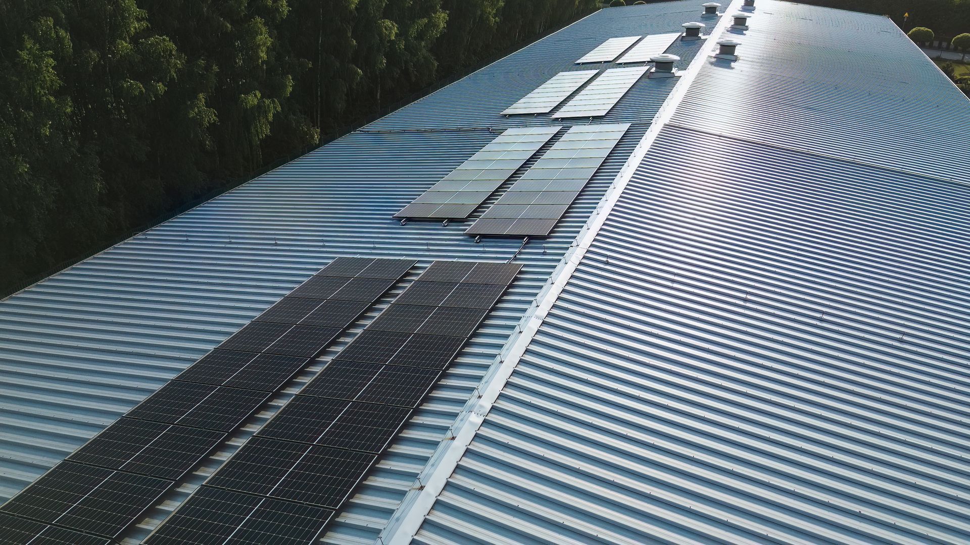 Panneaux solaires sur un toit en tôle ondulée. Photo prise en extérieur avec des arbres en arrière-plan.