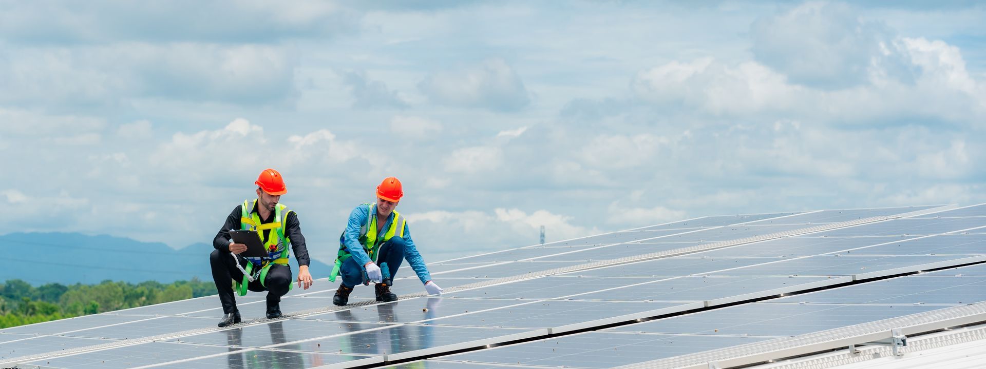 Deux professionnels sur des panneaux solaires qui portent des casques rouges