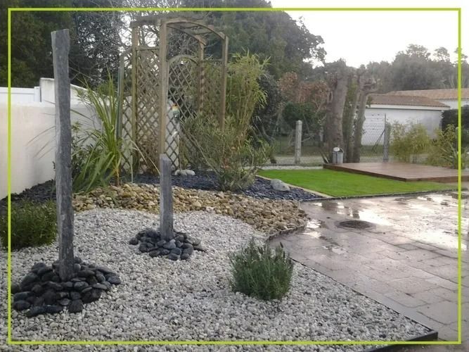 Aménagement paysager avec gravier gris, rochers noirs, treilles en bois et plantes vertes