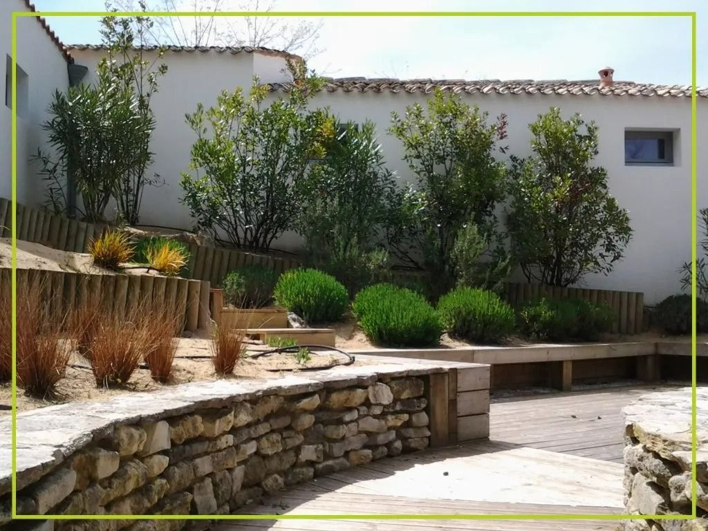 Jardin clos de murs en pierre, aménagé en terrasses, avec arbustes, arbres et éléments en bois