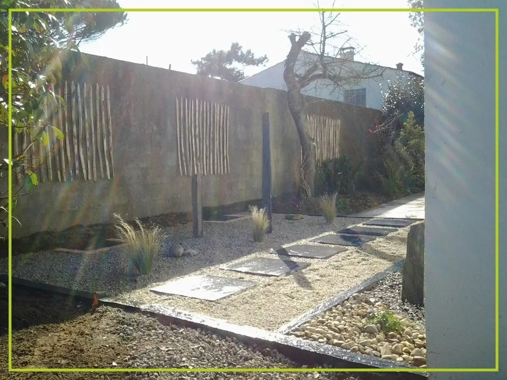 Allée de pierres dans un jardin zen entouré d'un mur texturé