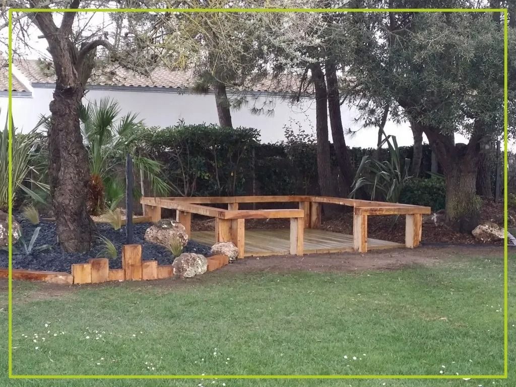 Terrasse en bois dans un jardin gazonné, entourée d'arbres et d'arbustes