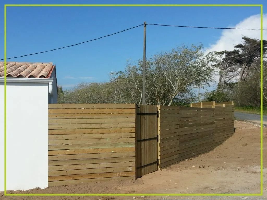 Clôture en bois avec un portail, à côté d'une maison blanche