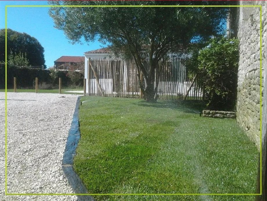 Une pelouse verte à côté d'une allée de gravier et d'une maison